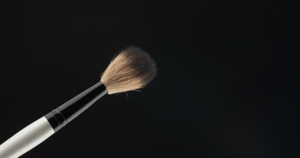Rotating makeup brush on a black background. Isolated - Video, Çekim