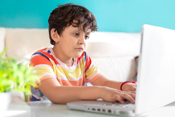 Petit garçon utilisant un ordinateur portable à la maison. Concept de technologie moderne et d'éducation en ligne. - Photo, image