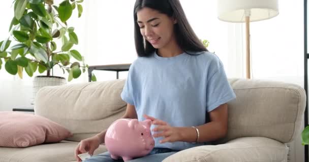 Mujer insertando dinero en alcancía en casa - Imágenes, Vídeo