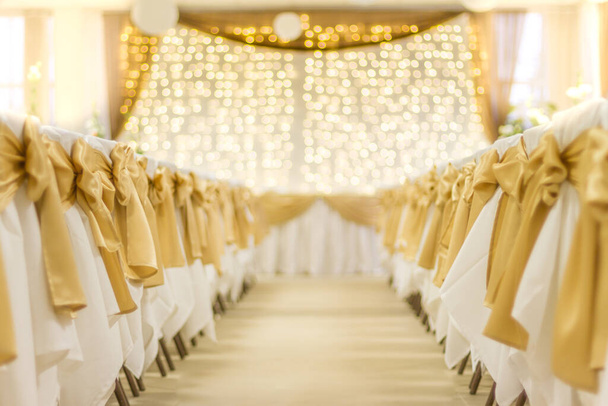 Konfiguracja wesela, stół i krzesła z rozmytymi złotymi światłami. Dekoracje ślubne, złote tło marzeń - Zdjęcie, obraz