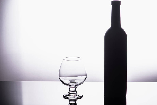 Bouteille de vin noir avec verre transparent isolé sur fond blanc. - Photo, image