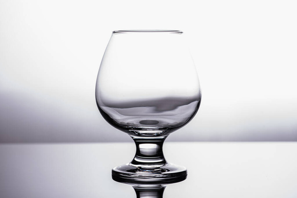 black and white photo, one transparent glass of cognac glass isolated on white background - Fotografie, Obrázek