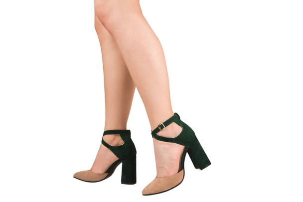 Jambes de femme en sandales vertes et beiges sur talons isolés sur fond blanc.  - Photo, image