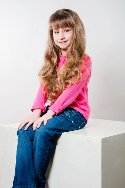 Little girl with long curly hair in a pink blouse - Fotó, kép