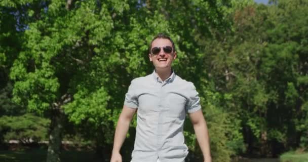 Молодой симпатичный мужчина поет и танцует в летнем парке 4k - Кадры, видео