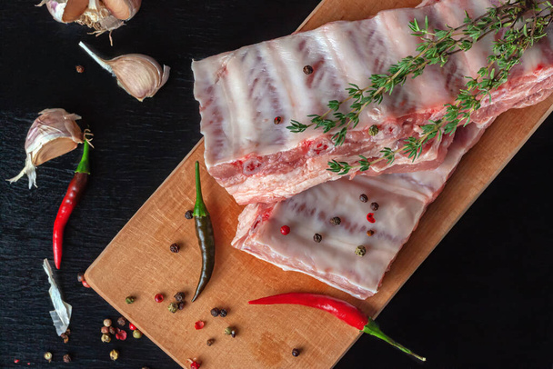 Raw pork ribs with spices and thyme on a dark wooden table - Fotoğraf, Görsel