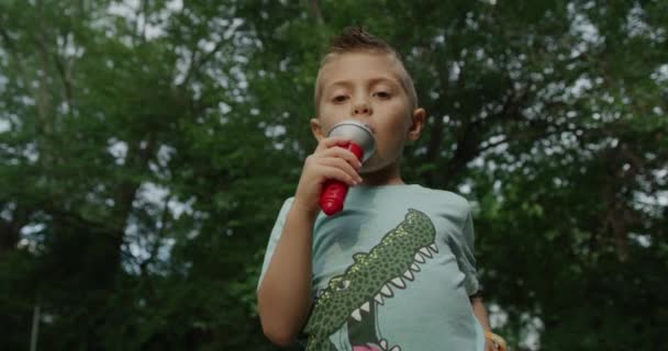 Słodki chłopczyk śpiewający z mikrofonem. Czerwona kamera kinowa 4k - Materiał filmowy, wideo