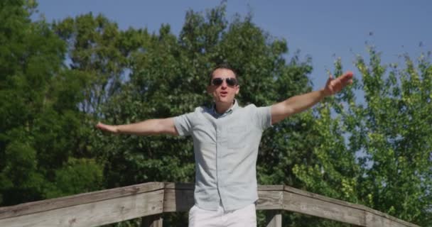Молодой симпатичный мужчина поет и танцует в летнем парке 4k - Кадры, видео
