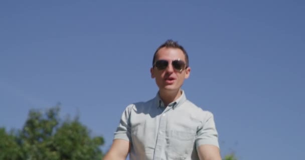 Młody ładny mężczyzna śpiewa i tańczy w letnim parku 4k - Materiał filmowy, wideo
