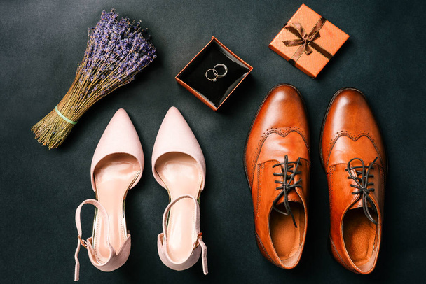 Detalles de la boda sobre un fondo negro. Zapatos, anillos de boda, una caja de regalo y un ramo de flores. Concepto de boda - Foto, imagen