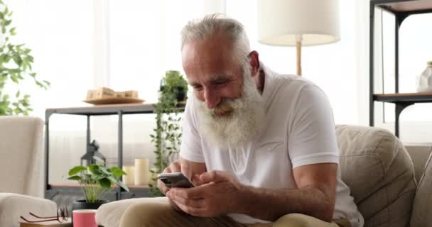 Old man receiving good news using mobile phone at home - Video