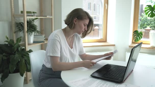 Mädchen überprüft Dokumente, findet Fehler, wirft zerknülltes Papier wütend in Laptop - Filmmaterial, Video