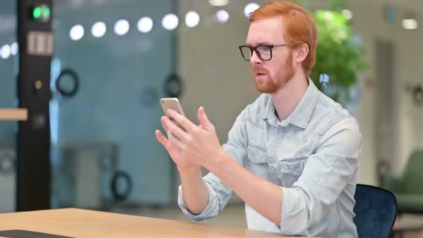 Masentunut punapää mies reagoi tappio älypuhelimeen toimistossa  - Materiaali, video