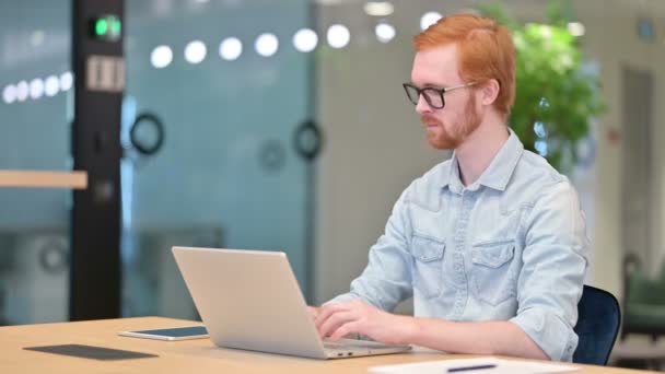 hüvelykujj fel alkalmi vöröshajú férfi dolgozik Laptop az irodában  - Felvétel, videó