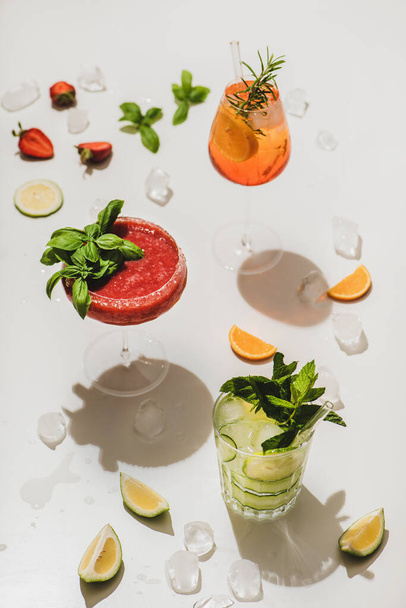 Popular bar summer ice alcoholic cocktails. Gin-tonic, Aperol Spritz and strawberry basil Margarita over plain white background, selective focus - Foto, Imagen