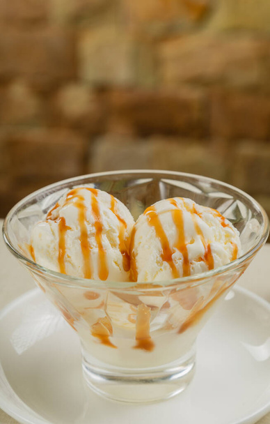 キャラメルとガラスの中の白いアイスクリーム. - 写真・画像