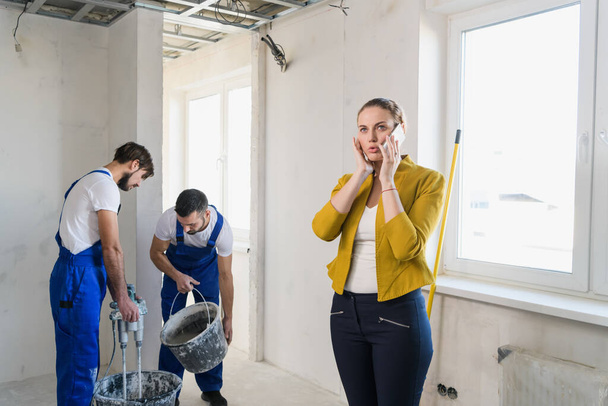 Geschäftsfrau telefoniert, Arbeiter kneten Zement - Foto, Bild