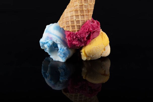 Hedelmät jäätelö kauhat yläpuolella kornetti, tarjoillaan useita värikkäitä lusikoita eristetty mustalla pohjalla. - Valokuva, kuva