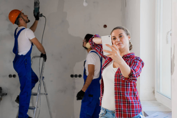 Mujer feliz tomando selfie junto con los trabajadores en ropa de trabajo - Foto, Imagen