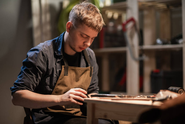 Ein junger Lehrling fertigt Rohlinge für die Schuhproduktion in der Werkstatt. - Foto, Bild