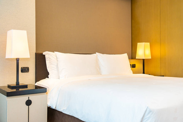 Біла зручна подушка і ковдра на ліжку зі світлою лампою прикраса інтер'єру спальні
 - Фото, зображення