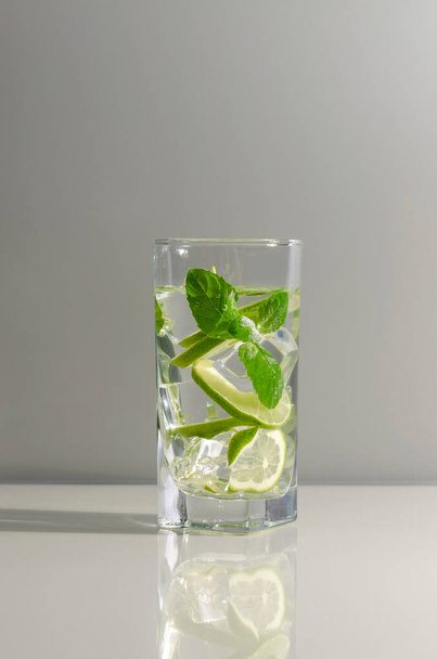 Mojito cocktail with lime and mint in tall glass. Fresh mojito in glass on a gray background. Copy space - Foto, Bild