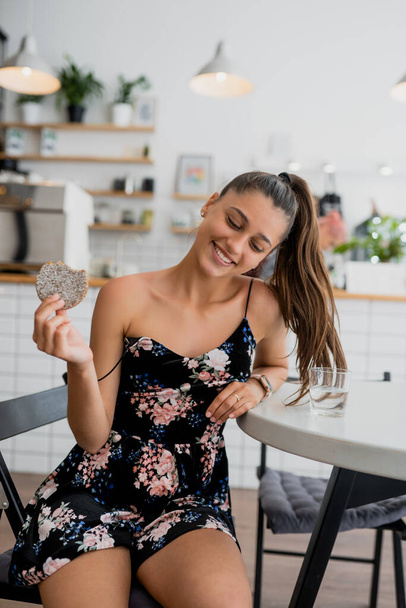 Happy smiling girl holds cookie in a cozy cafe. - Foto, afbeelding