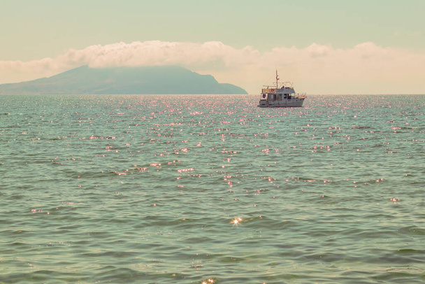 Pleasure boat yacht in a calm azure sea on the background of the horizon with mountains. - Foto, Bild