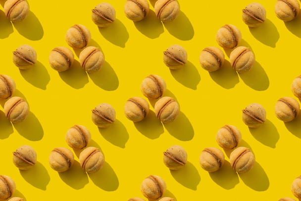 Um padrão repetitivo de biscoitos de noz em um fundo amarelo. Textura sem costura. - Foto, Imagem