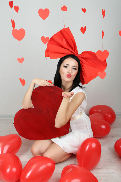 Attractive young woman with big heart and balloons in room on Valentine Day - Fotó, kép