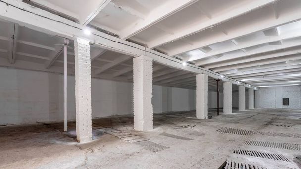 Průmyslový interiér budovy s bílými cihlovými stěnami, betonovou podlahou a prázdným prostorem pro vystavování výrobků nebo průmyslové zázemí - Fotografie, Obrázek