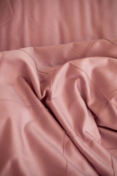 Unmade empty bed. Bed linen is pink. - Foto, afbeelding