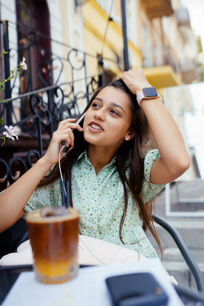 Aantrekkelijk meisje zitten buiten straat cafe, praten smartphone - Foto, afbeelding