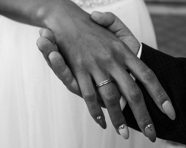 Bräute Hand mit einem eleganten Ehering mit Diamanten aus Weißgold an einem Strauß ihrer Pfingstrosen - Foto, Bild