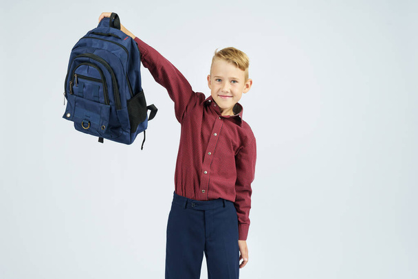 A schoolboy holds a schoolbag lifting it up. Education concept - Foto, Imagen