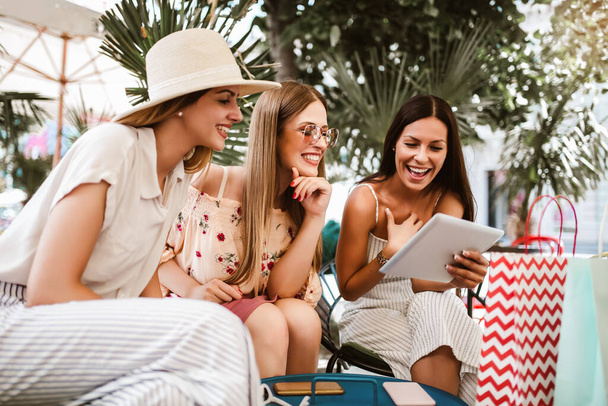 Mujeres jóvenes felices utilizando tableta digital en la cafetería al aire libre - Foto, imagen