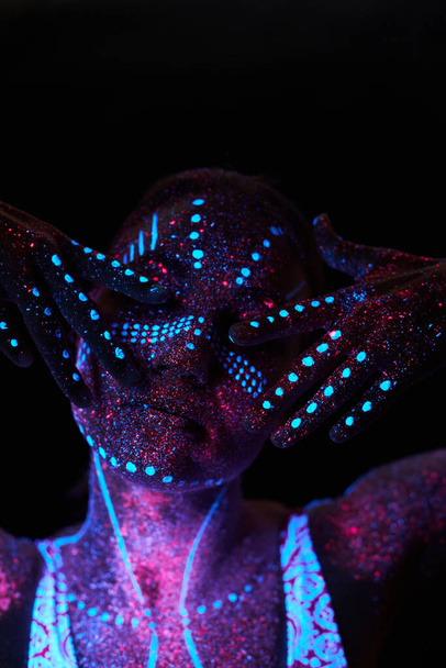 Woman does yoga, hand movement, body warm-up. Art girl cosmos in ultraviolet light. Entire body is covered with colored droplets. Astral yoga. Noise, out of focus - Zdjęcie, obraz