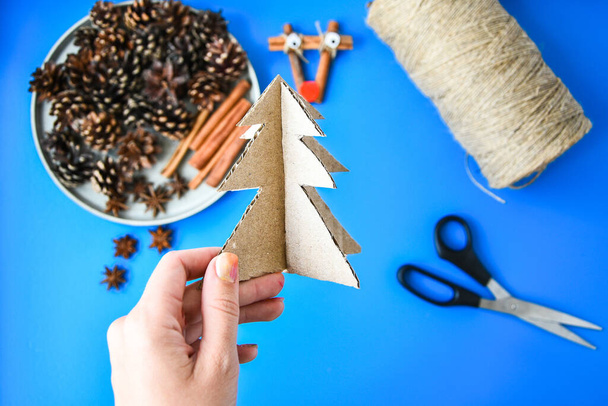 Draufsicht der Herstellung kleiner Weihnachtsbaum aus Pappe. Kinderkunstprojekt, ein Basteln für Kinder. DIY-Konzept. Schritt für Schritt 6. Natürliche handgefertigte Weihnachtsdekorationen. Null Abfall Weihnachten - Foto, Bild
