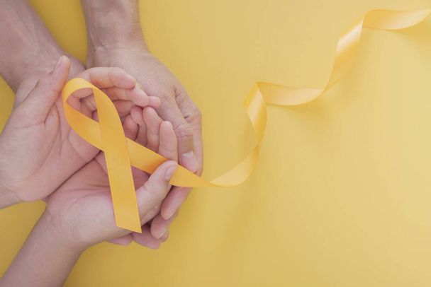 adult and child hands holding yellow gold ribbon, Sarcoma Awareness, Bone cancer, childhood cancer awareness, world suicide prevention day, September Yello - 写真・画像