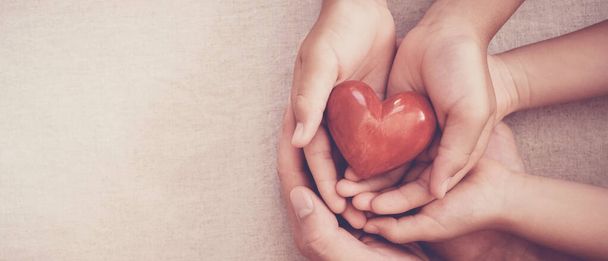 hands holding red heart, heart health, charity volunteer donation, CSR responsibility, world heart day, world health day, family day, adoption foster care home, all lives matter, no to racism concept - Fotografie, Obrázek