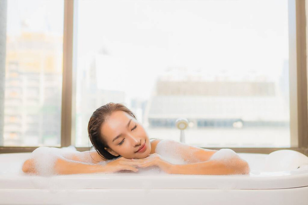 Retrato hermosa joven mujer asiática relajarse disfrutar de tomar un baño en la bañera en el interior del baño - Foto, Imagen