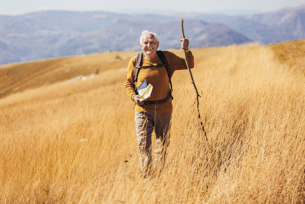 Senior man on hike through beautiful countryside in autumn. - Foto, imagen