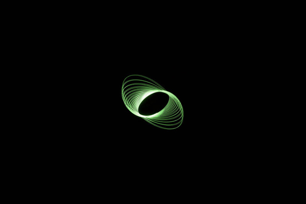 green elliptical light painting photography, long exposure, ripples and waves against a black background - Photo, Image