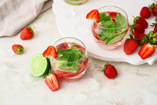 Glasses of tasty strawberry mojito on light background - Photo, Image