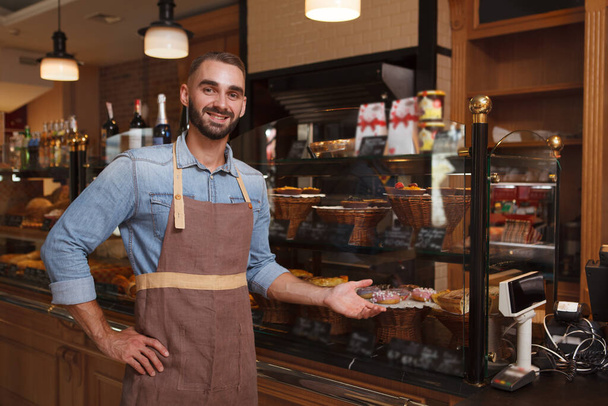 Cheerful male baker welcoming you at his bakery store, copy space - Foto, immagini