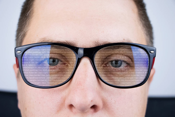 The programmer's glasses reflect lines of code. Programming, development of applications, sites and other things. Software development concept - Foto, Imagem