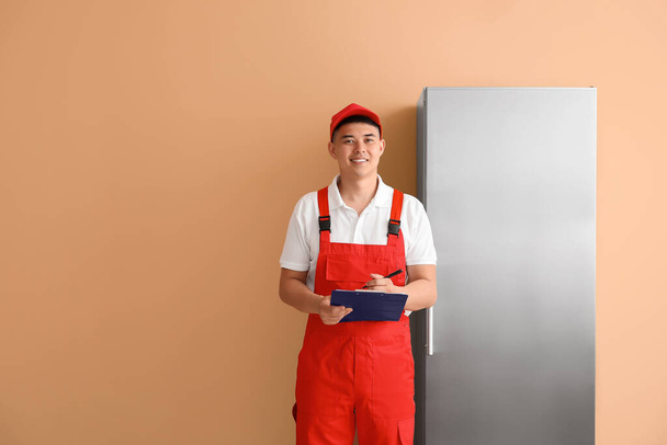 色の背景に冷蔵庫の近くの修理サービスの労働者 - 写真・画像