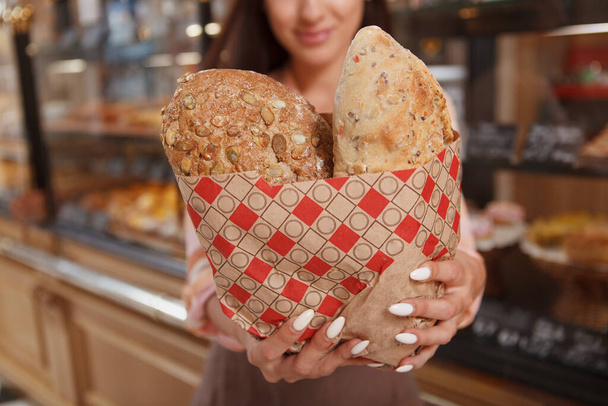 Gesneden close-up van heerlijke broodjes in de handen van vrouwelijke bakker in de lokale bakkerij - Foto, afbeelding