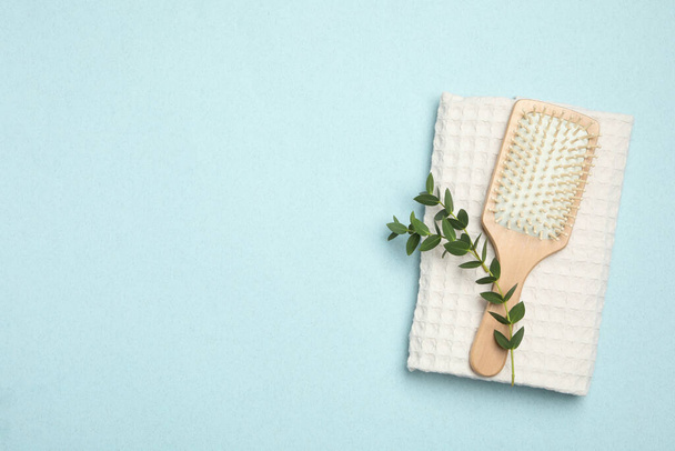 Modern paddle hair brush and plant on light background, flat lay. Space for text - Foto, afbeelding