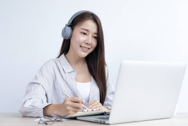 Asian woman is studying online through her laptop in her home, stay home, New normal, Covid-19 coronavirus, Social distancing, Internet learning. - Photo, Image